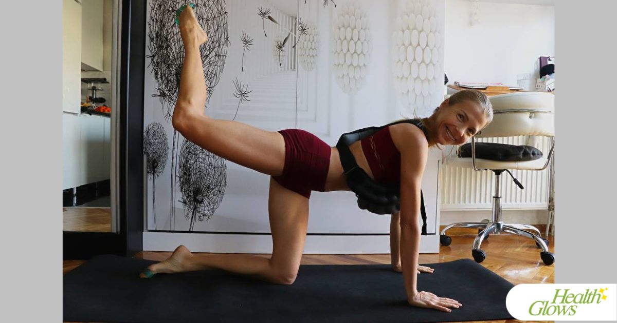 Marina from Health Glows on all fours, with one leg lifted, knee bent. Marina is wearing a weighted vest.