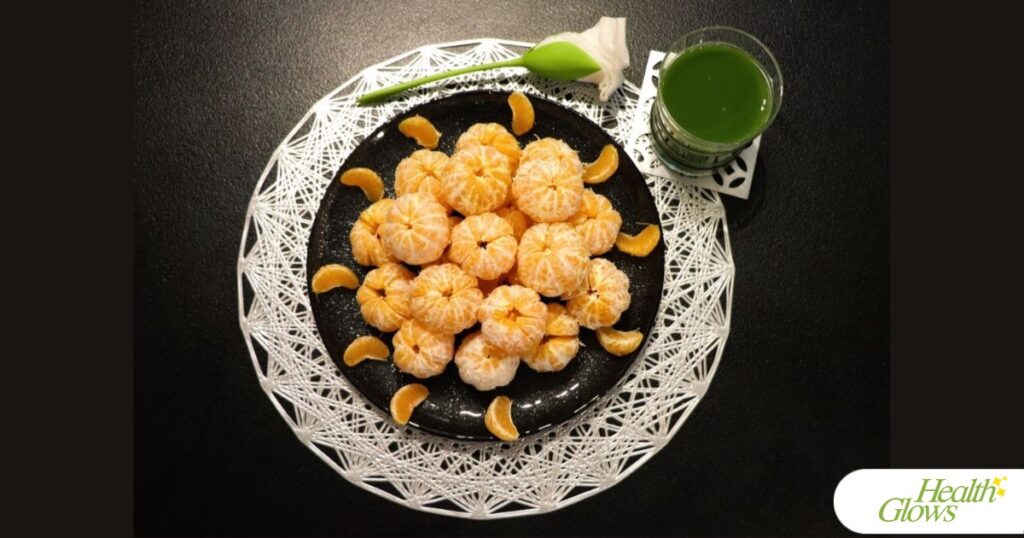 A plate of peeled clementines and a glass of green juice.