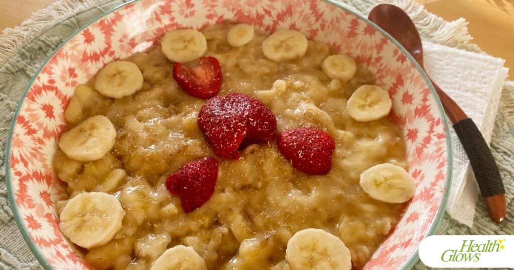 A bowl full of mashed bananas with strawberries, spiced with freshly grated nutmeg. A wooden spoon is next to the bowl.