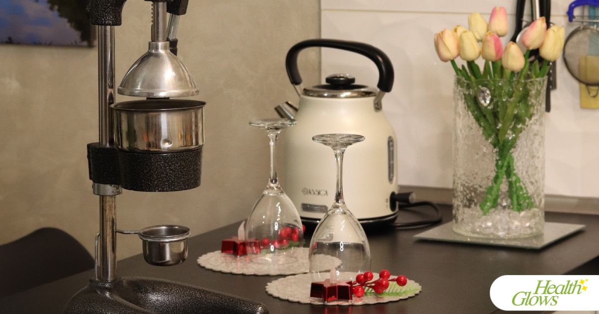 Two empty wine glasses standing next to a pomegranate press.
