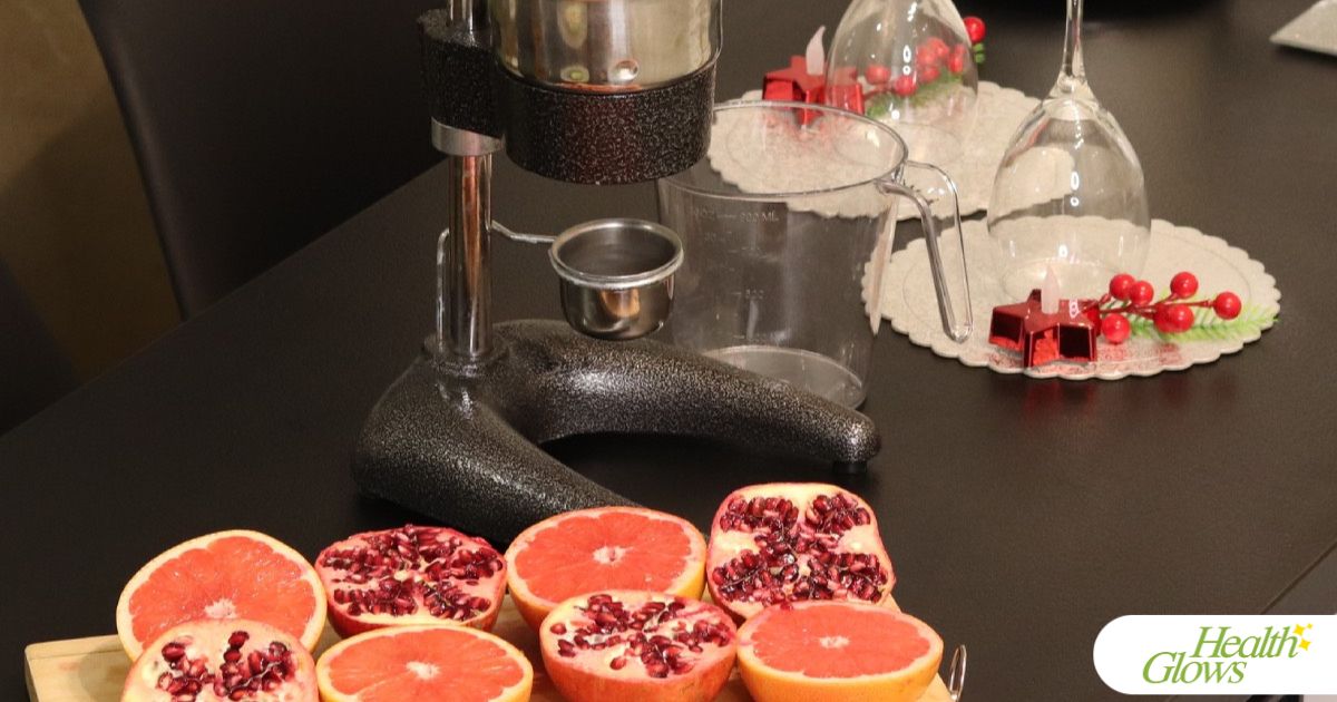 Halved pomegranates, oranges and grapefruits laid out next to a pomegranate press.