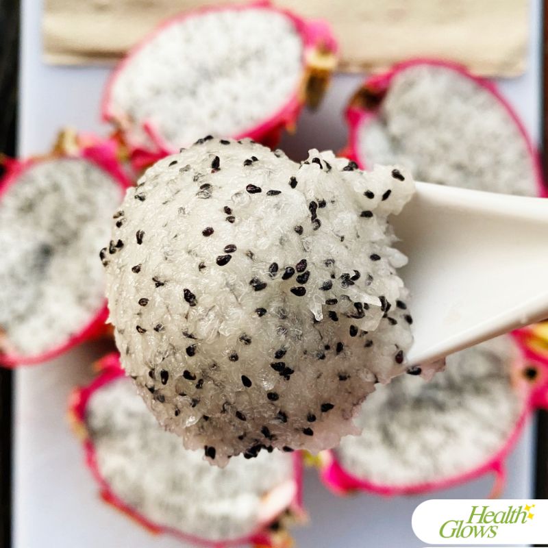 White flesh dragon fruit in a spoon. There are open dragon fruit halves on a plate behind the spoon.