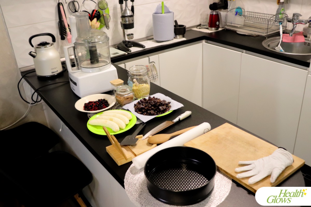 Ingredients and equipment for making a raw vegan banana-berry cake laid out on the kitchen counter.