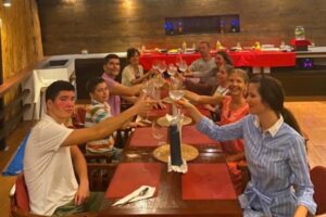 The Health Glows Thai Retreat 2025 group sitting at the dinning table and toasting with vine glasses filled with coconut water.
