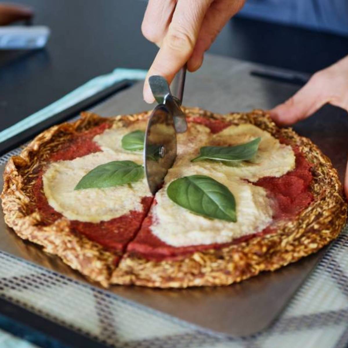 Marina from Health Glows is cutsting a raw vegan pizza that is on the dehydrator shelf.